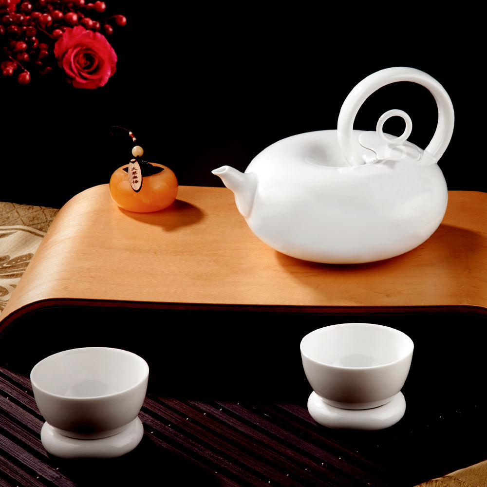 圓好夢白瓷一壺兩杯組置於深色茶桌,搭配橘色茶席擺件呈現雙人共飲情境