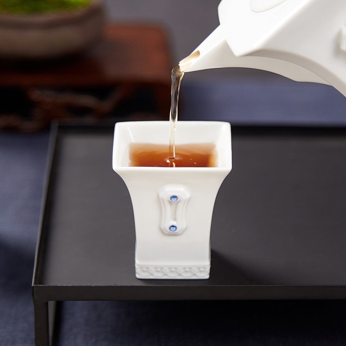 明珠在握白瓷茶壺斟入方口茶杯,展示茶具出水表現與杯身水鑽細節