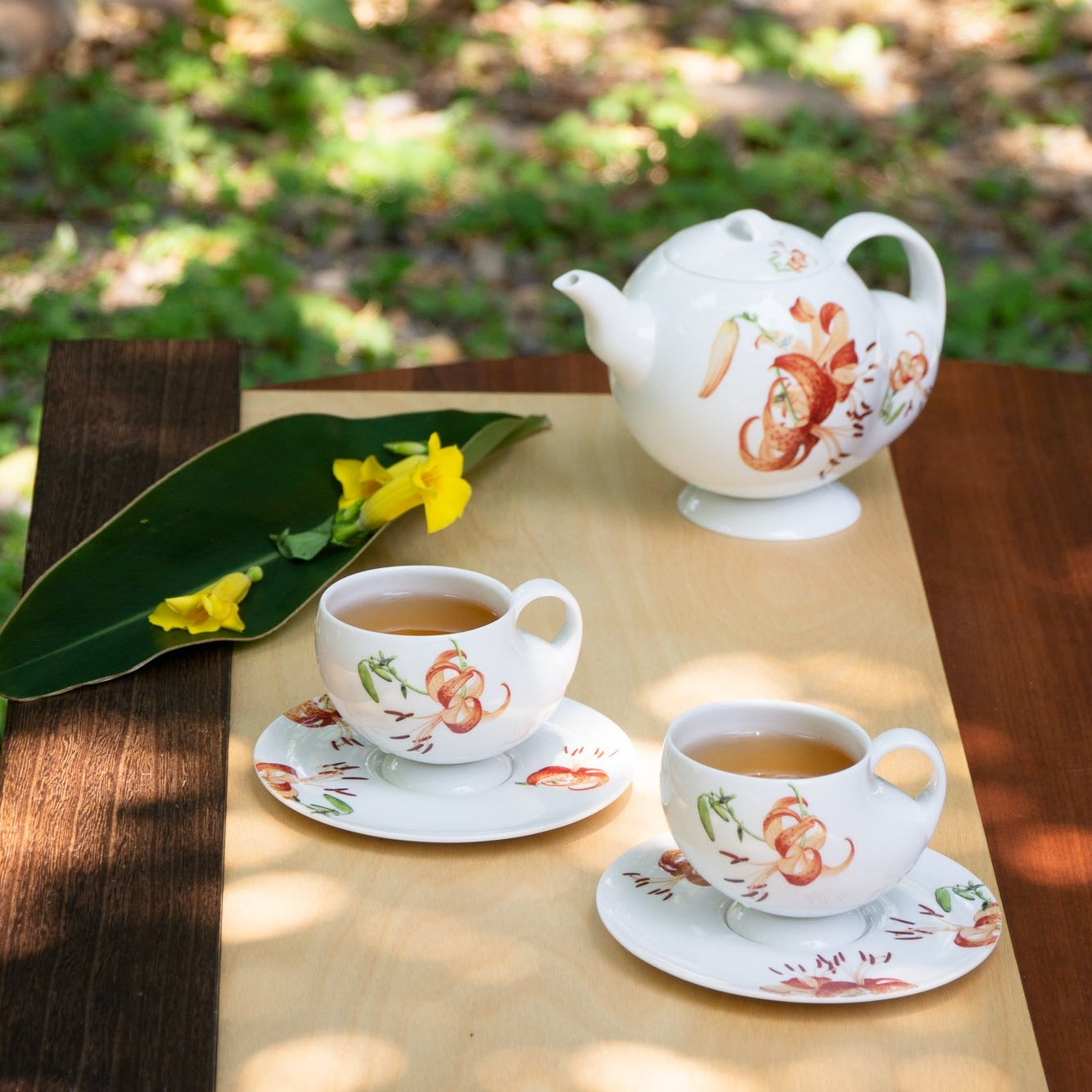 青春 In Bloom 百合白瓷茶具組,白瓷茶壺與茶杯於戶外自然光下展示,展現百合花盛放的生命力