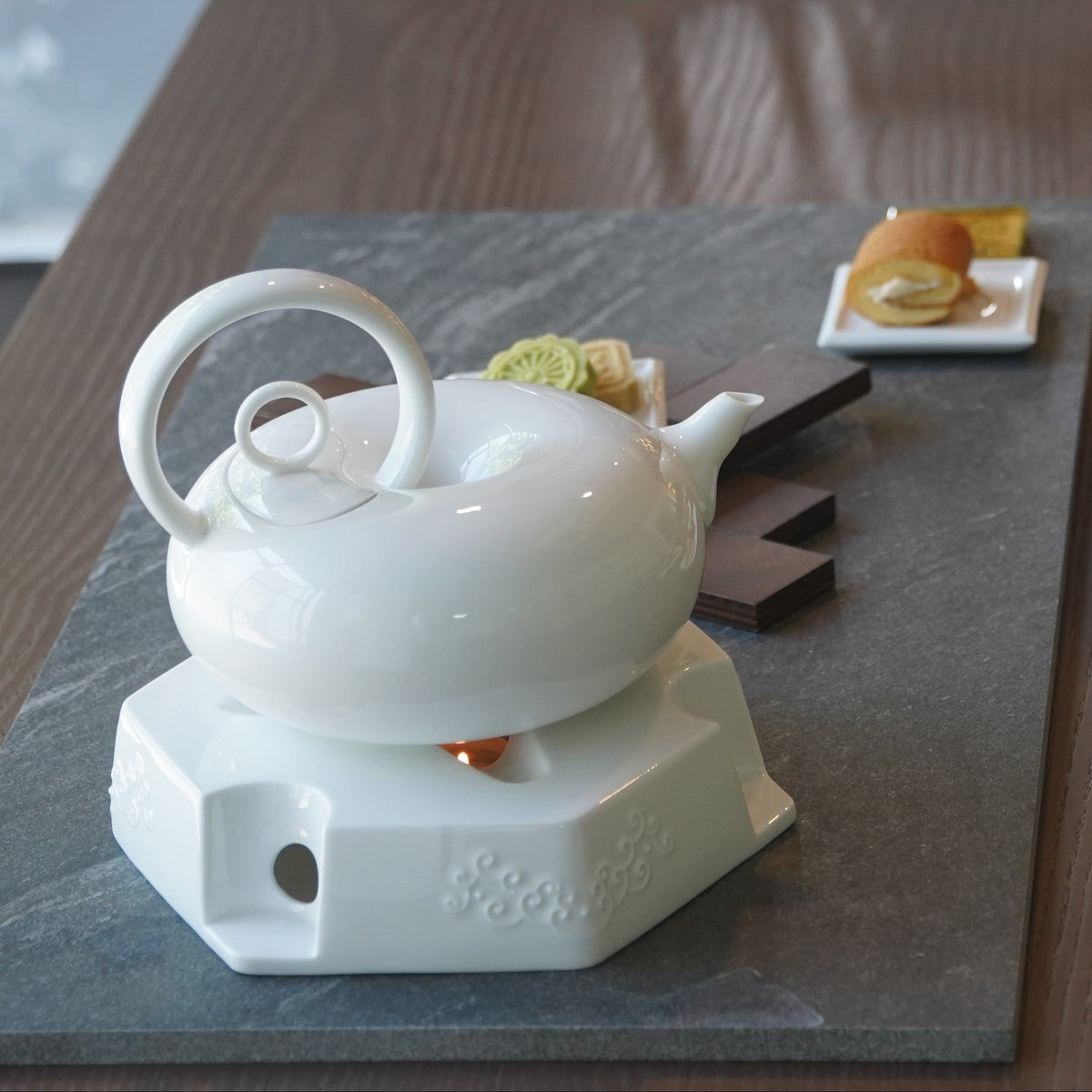 圓好夢白瓷茶具置於白色高台茶盤，搭配茶點與綠色背景形成品茶情境