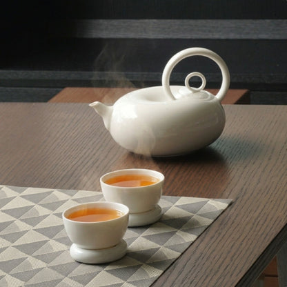 圓好夢白瓷茶具一壺兩杯組，渾圓壺身與環形把手陳列於深色木質茶桌