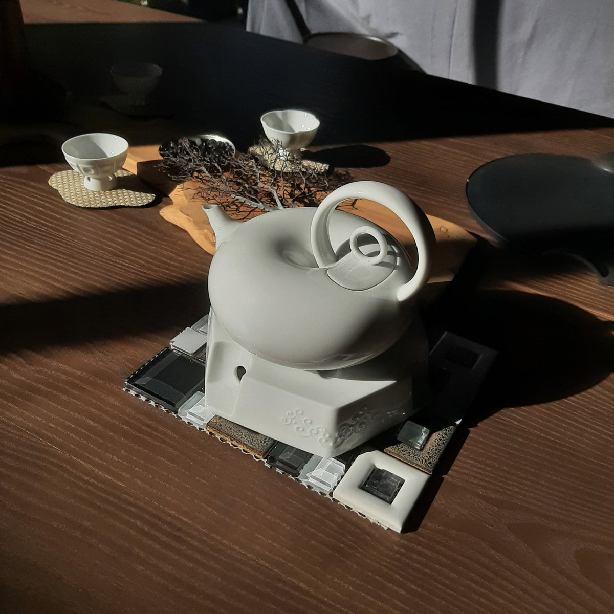 圓好夢白瓷茶壺置於現代茶席底座，搭配茶杯與茶點呈現完整品飲空間