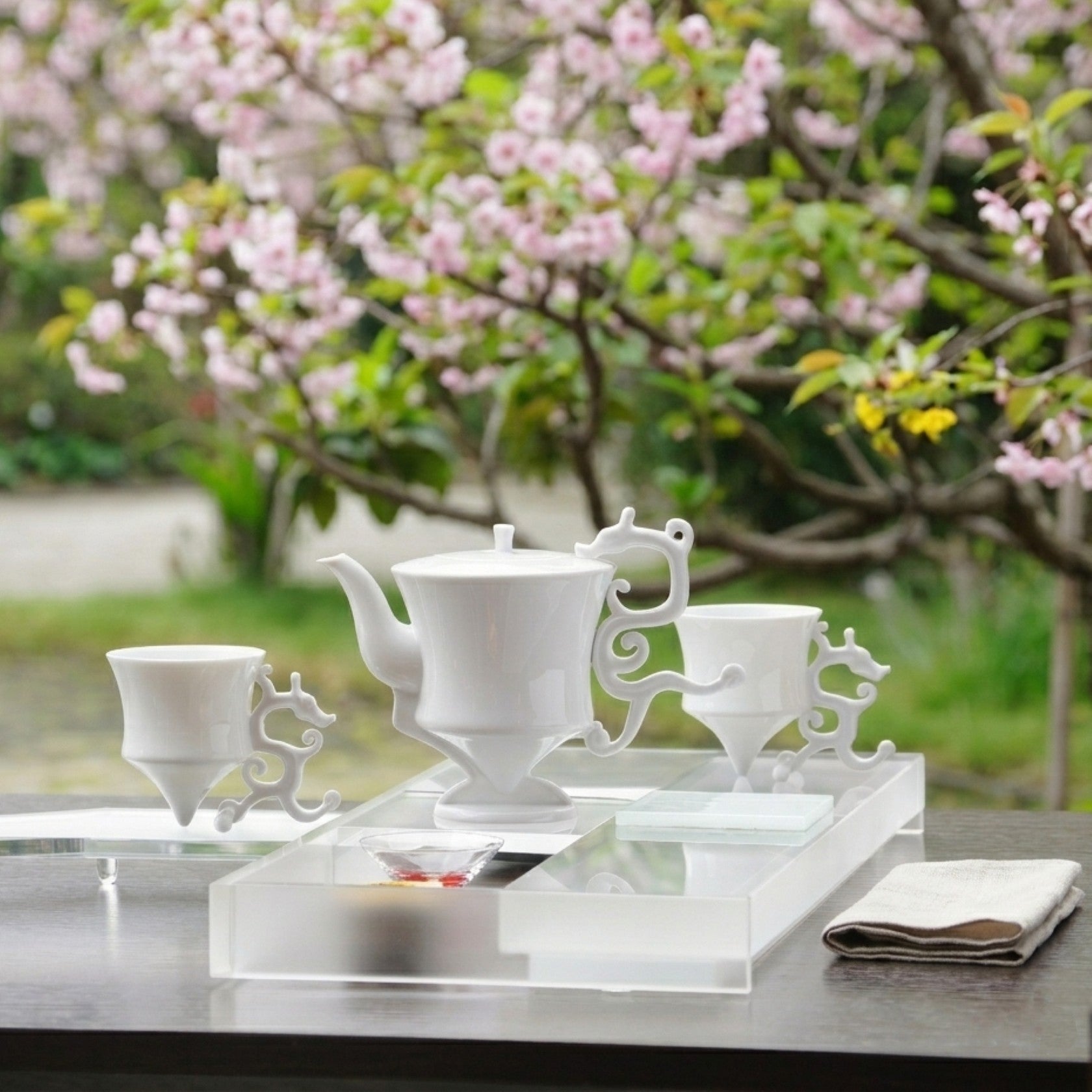 龍尊壺杯組白瓷茶具，戶外櫻花背景，春日品飲場景，展示整組氣韻，八方新氣