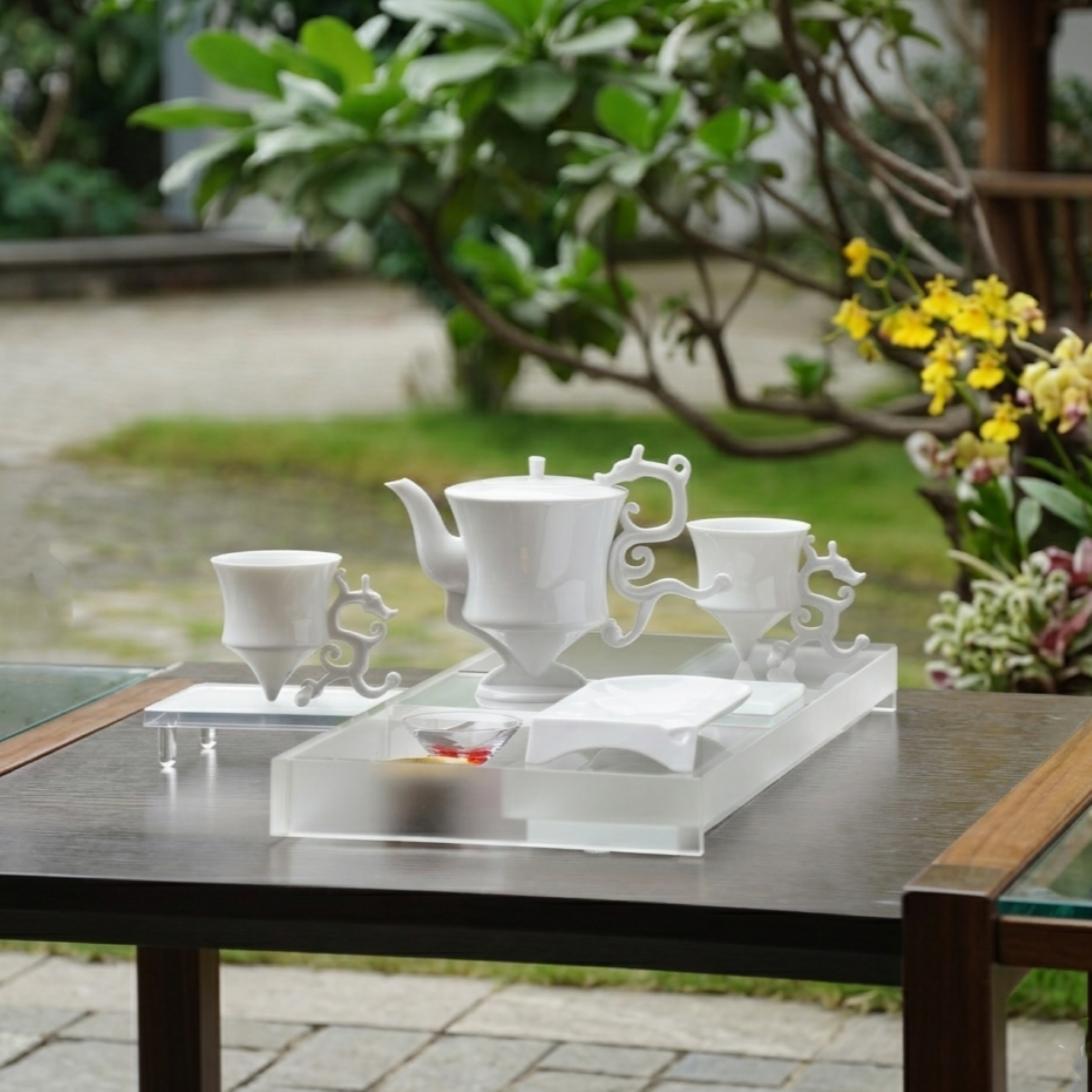 龍尊壺杯組白瓷茶具，戶外庭院木桌場景，壓克力底座陳設，花木背景，八方新氣 NewChi Porcelain