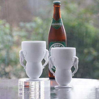 萬象一新白瓷大象把手杯與啤酒瓶搭配，展示以白瓷杯飲啤酒使用情境，八方新氣