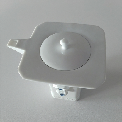 明珠在握白瓷茶壺頂視圖，壺蓋、方形壺口與俐落壺嘴構成現代幾何造型