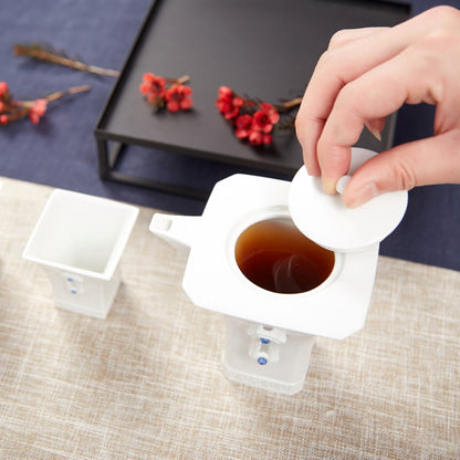 明珠在握白瓷茶壺沖泡情境，熱水注入壺中並搭配方形茶杯與紅色茶席花果